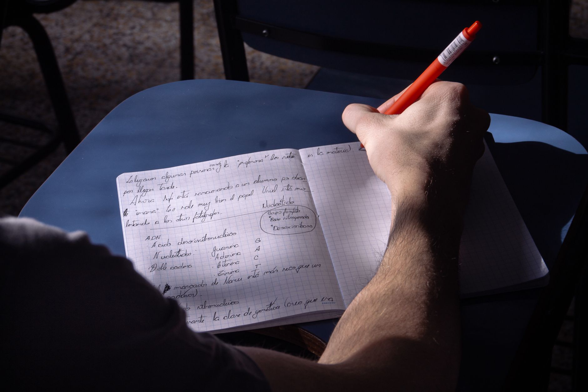 Une personne prend des notes avec attention pendant une session de formation, éclairée par la lumière naturelle.